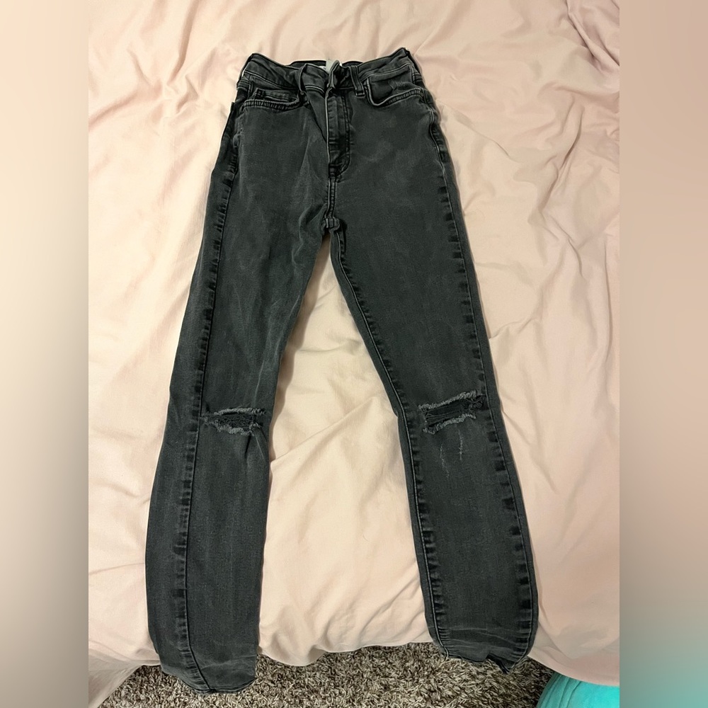 High waisted black skinny jeans with two holes at the knees.